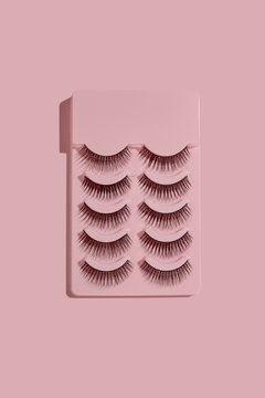 a pink box with five pairs of false lashes on pink background top view