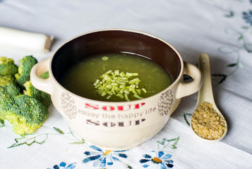Sopa de verduras decorada con brócoli, puerros y pasta de estrellas con fondo de mantel