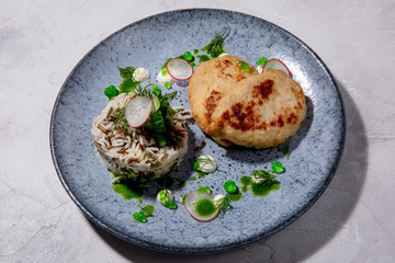 Pike cutlet. Pike fillet, onion, salt, seasonings and spices, side dish of rice and fresh salad, sour cream. European cuisine. The work of a professional chef. Dish from a restaurant menu. Side view