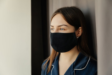 Close up portrait of a caucasian brunette in a protective medical mask on her face looking at...