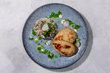 Pike cutlet. Pike fillet, onion, salt, seasonings and spices, side dish of rice and fresh salad, sour cream. European cuisine. The work of a professional chef. Dish from a restaurant menu. Top view