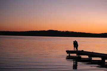 Naklejka na ściany i meble Couple silouette on a pier at sunset