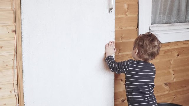 Boy closes a wooden door