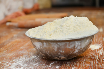 wheat flour is in an iron plate on a wooden table