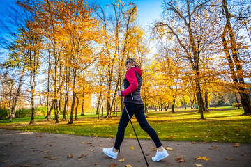 Nordic walking - middle-age woman working out in city park
