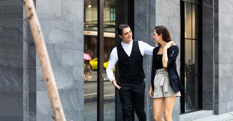 Business colleagues couple walking on street while talking to each other. Young happy business couple walking outdoor office building