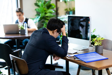 Portrait of serious and pensive Asian business people working with desktop computer at coworking space. sad man concept