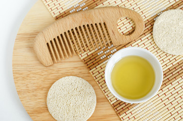 Olive oil, loofah sponge and wooden hairbrush. Ingredients for preparing homemade mask. Natural beauty treatment recipe and zero waste concept. Top view, copy space.