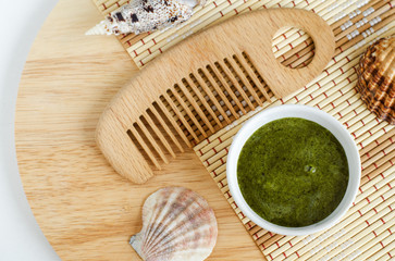 Diy green mask (scrub) with spirulina extract and wooden hair brush. Ingredients for preparing homemade cosmetics. Natural beauty treatment recipe and zero waste concept. Top view, copy space.