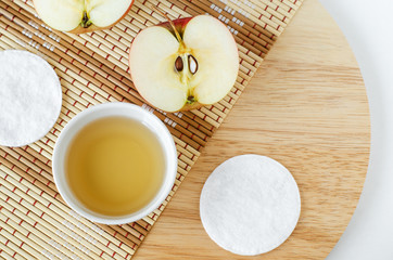 Apple juice (vinegar) and cotton pads. Ingredients for preparing homemade mask or face toner. Natural beauty treatment recipe and zero waste concept. Top view, copy space