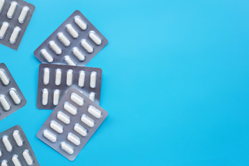 Capsule medicines in blister pack on blue background. Copy space