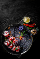 sushi roll with tuna, cream cheese, cucumber, rice in plate on black wooden table background