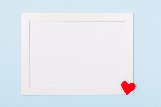 White frame empty blank picture on light blue background . Copy space free space for text. Holiday card concept. Mock up. Greeting. Mother's Day. St Valentine's Day. Love . Wedding invitation. 