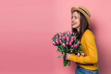 Young woman with  bouquet of tulips on color background