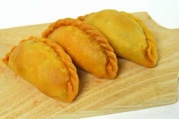 3 crispy pastels with a white background on a wooden cutting board