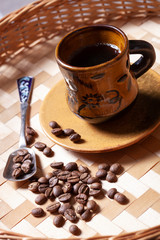 Cup of coffee on a wicker tray in a rustic style and coffee beans close-up