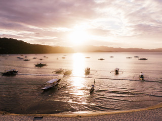 Several Boats anchored at a tropical beach in south east asia while sunset