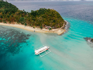 A white boat anchored in front of the tropical island in the philippines