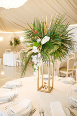banquet table is decorated with plates, cutlery, glasses, candles and flower arrangements