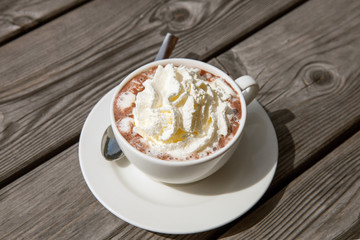 Cup of cocoa with whipped cream on a wooden table