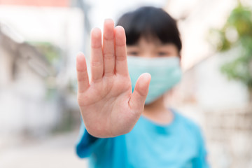 Asian Child girl wear medical face mask during pandemic Coronavirus Covid-19 outbreak and show stop hands gesture for stop corona virus outbreak ,stay at home to quarantine motivational phrase