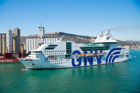 Barcelona, Spain - March 30, 2016: ship or liner GNV Rhapsody Genova in sea harbor on mountain landscape. Cruise ship destination and trip. Travelling by sea on ship. Big passenger ship