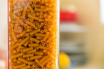raw italian macaroni pasta inside clear storage container