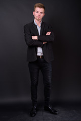 Portrait of young handsome blond bearded businessman in suit