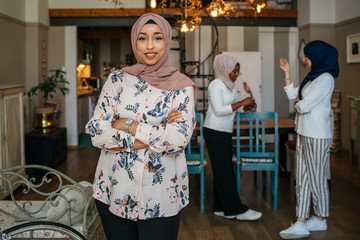 Portrait of one Muslim woman with hijab at home - Two arab millennials talking in an apartment and...
