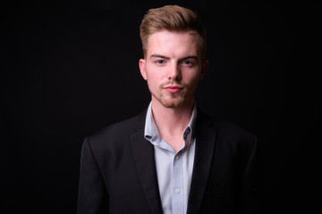 Portrait of young handsome blond bearded businessman in suit