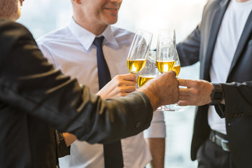 Picture of co-worker and business colleague celebrate company deal success. They hold champagne glass in their hand to bottom up. Other colleague wear suit and tie while one man wear white shirt.