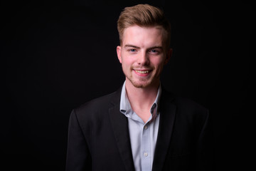 Portrait of young handsome blond bearded businessman in suit