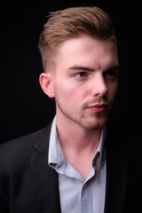 Portrait of young handsome blond bearded businessman in suit
