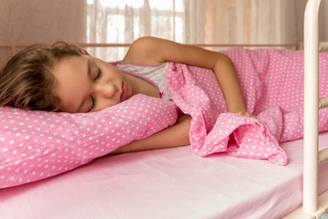 Obraz na płótnie Canvas Child little girl sleeps in a tubular bed covered with pink blanket in pink sheets and pillow.