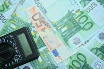 Multimeter on the euro banknotes background. The concept of electricity and electricity bills.