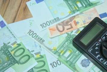 Multimeter on the euro banknotes background. The concept of electricity and electricity bills.