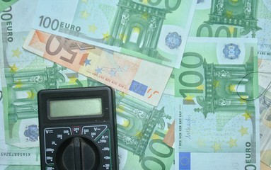 Multimeter on the euro banknotes background. The concept of electricity and electricity bills.