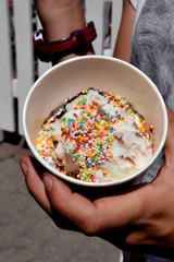ice in a paper cup with a chocolate-cream and cream flavor with colorful balls