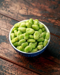 Green Broad Beans in a blue bowl on wooden table. healthy food