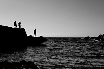 Black and white silhouettes on stones and sea. 