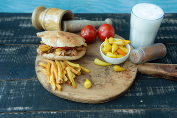 Doner kebab (shawarma or doner wrap). Grilled chicken on lavash (pita bread) with tomatoes, green salad and peppers on the old wooden background. Middle Eastern food, arabic fast food concept