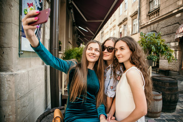 Three young women are walking in the city and having fun. Summer mood
