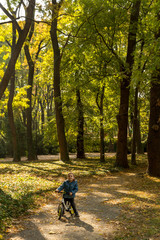Fototapeta premium Small child driving bicycle at asphalt road in fall season.