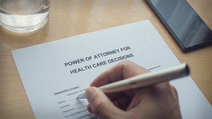 power of attorney for health care decisions. Writing a power of attorney form. Hand holding a pen and writing a form. - obrazy, fototapety, plakaty