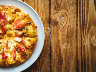 Homemade pizza just got out of the hot oven. Empty on the wooden table