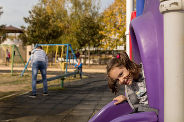 Fototapeta na wymiar A portrait of smiling little girl enjoys playing in a children playground. Having fun outdoor.