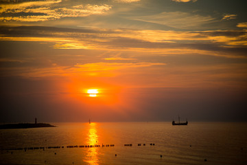 Zachód słońca nad morzem z okrętem w tle
