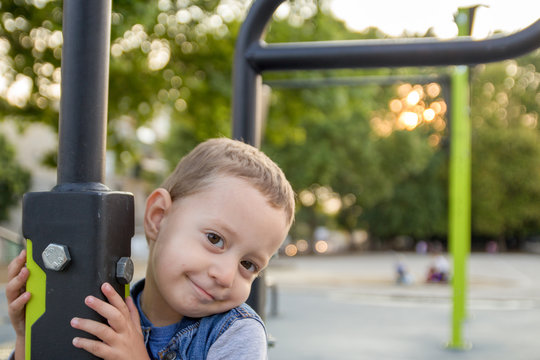Happy small boy staying near brachiating bar at a school yard. Selective focus.