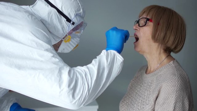 Coronovirus test family risk group. Doctor in a protective suit takes a swab from the throat from an elderly woman pensioner then from her husband. Non-invasive diagnostic method by PCR reaction
