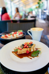 Cheesecake with berries and caramel and mint on terrace bokeh